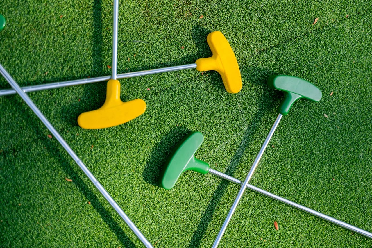 Vibrant yellow and green mini golf putters arranged on a lush green turf, perfect for leisure scenes.